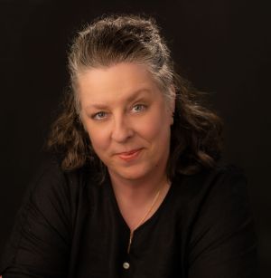 Image of a woman with one eyebrow raised, smirking, while leaning on the back of a chair